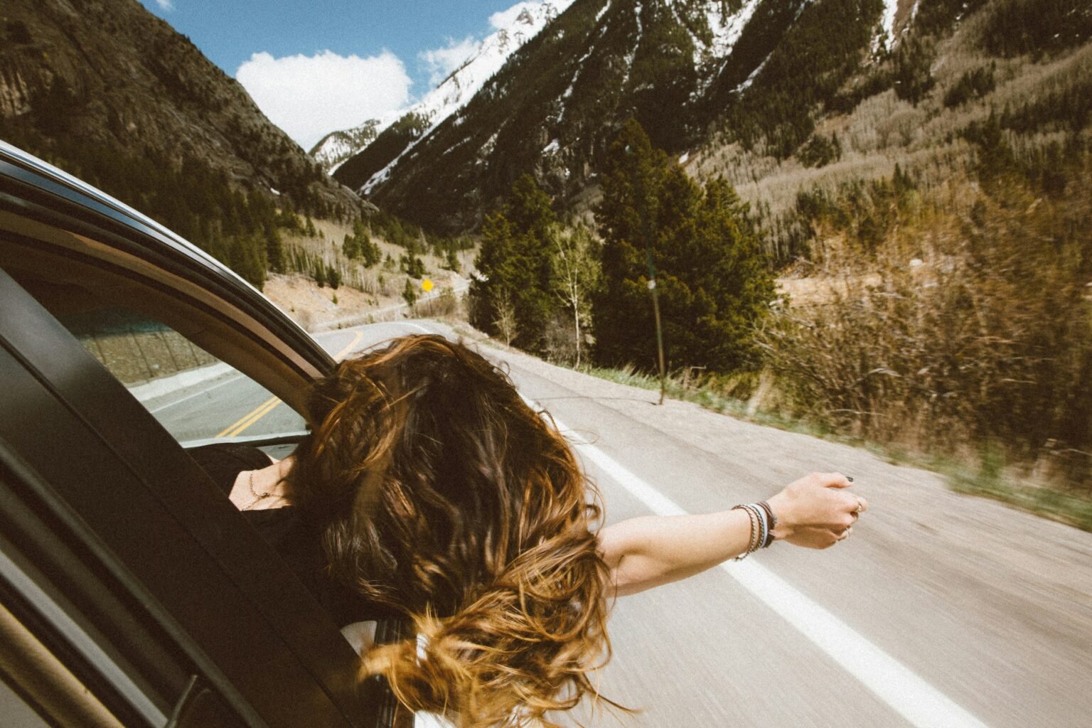 Five Safe Travel Destinations in Asia for the Year 2024 woman riding on vehicle putting her head and right arm outside the window while travelling the road