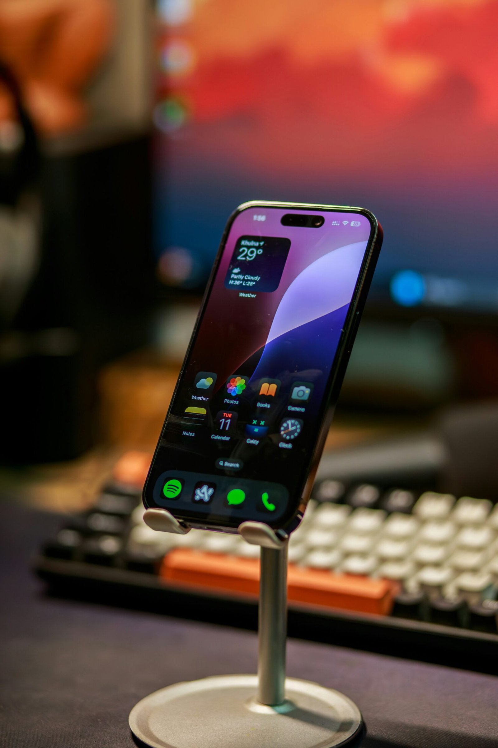 a cell phone on a stand next to a keyboard