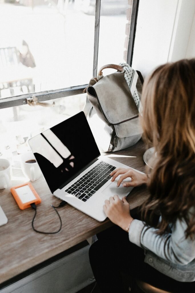 Strategies for Effective Remote Team Management girl wearing grey long-sleeved shirt using MacBook Pro on brown wooden table